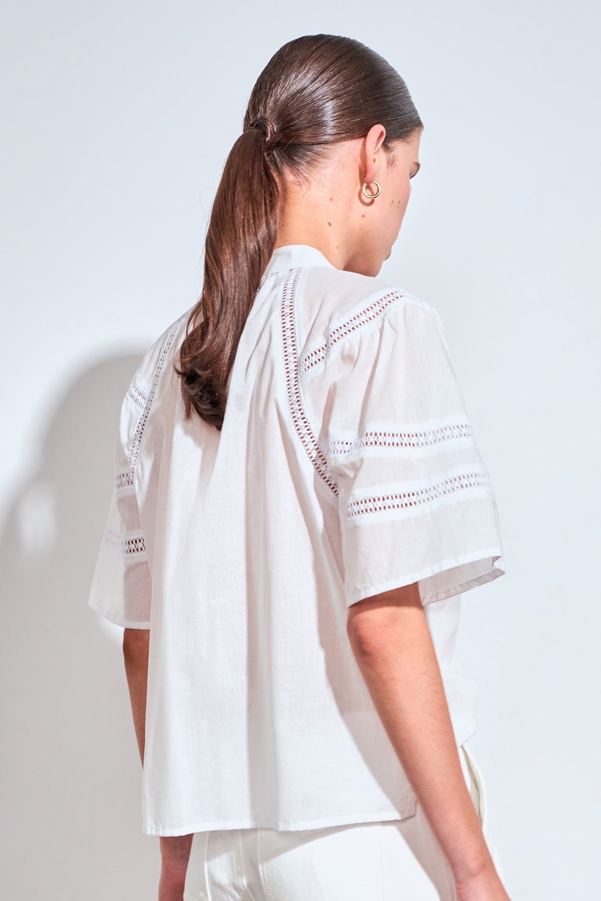 ZOE KRATZMANN PULSE TOP PORCELAIN - A white short-sleeve blouse with delicate eyelet embroidery across the chest and shoulders.