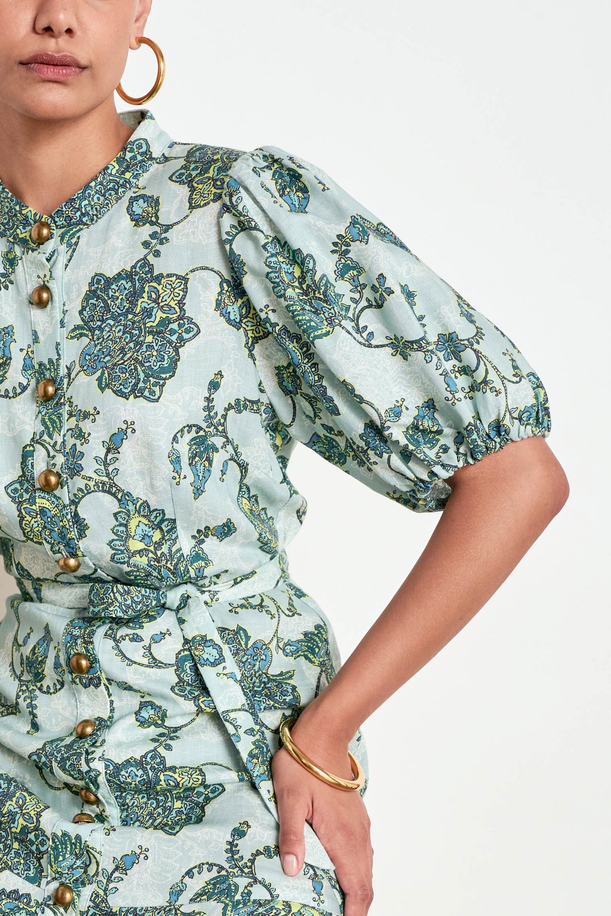 ZOE KRATZMANN CASCADE DRESS FERN PAISLEY - A light green midi dress with a blue and green floral print, featuring puff sleeves, a button-up front, and a tie-waist detail