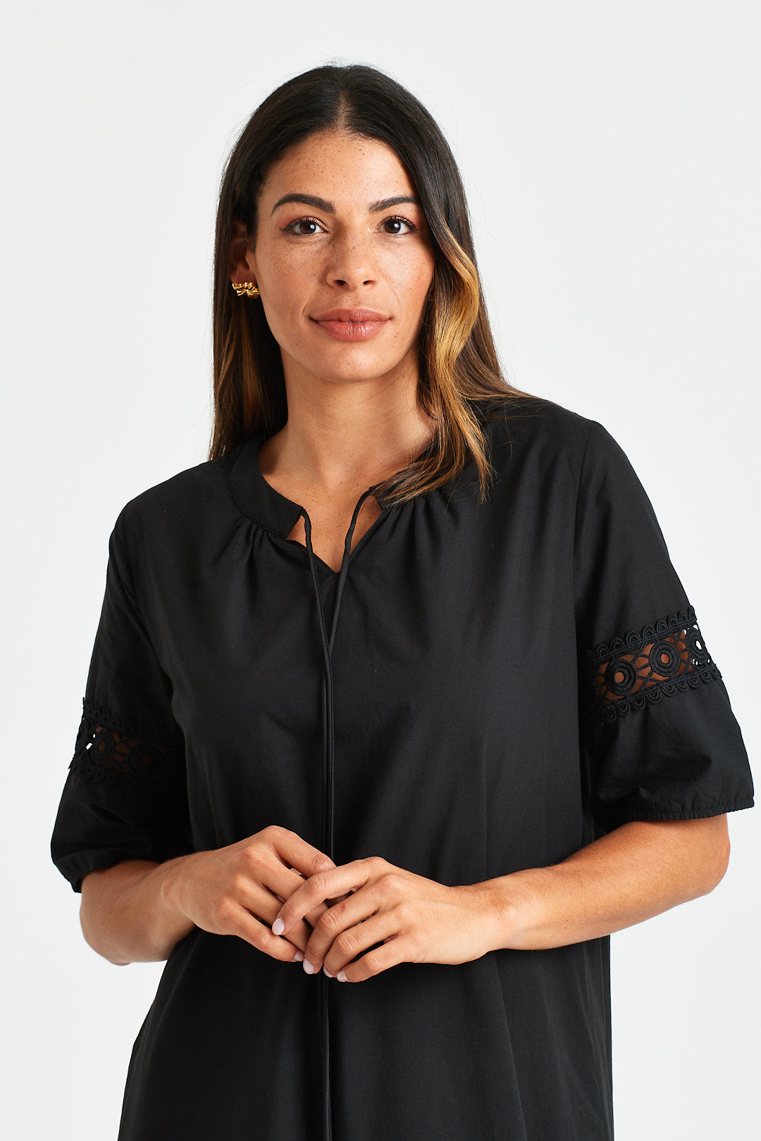GERVAIS DRESS Woman wearing a black dress with lace sleeves against a white background