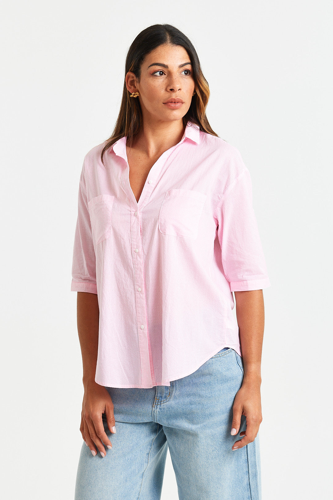 LYDIE SHIRT Woman wearing a light pink shirt and blue jeans on a white background