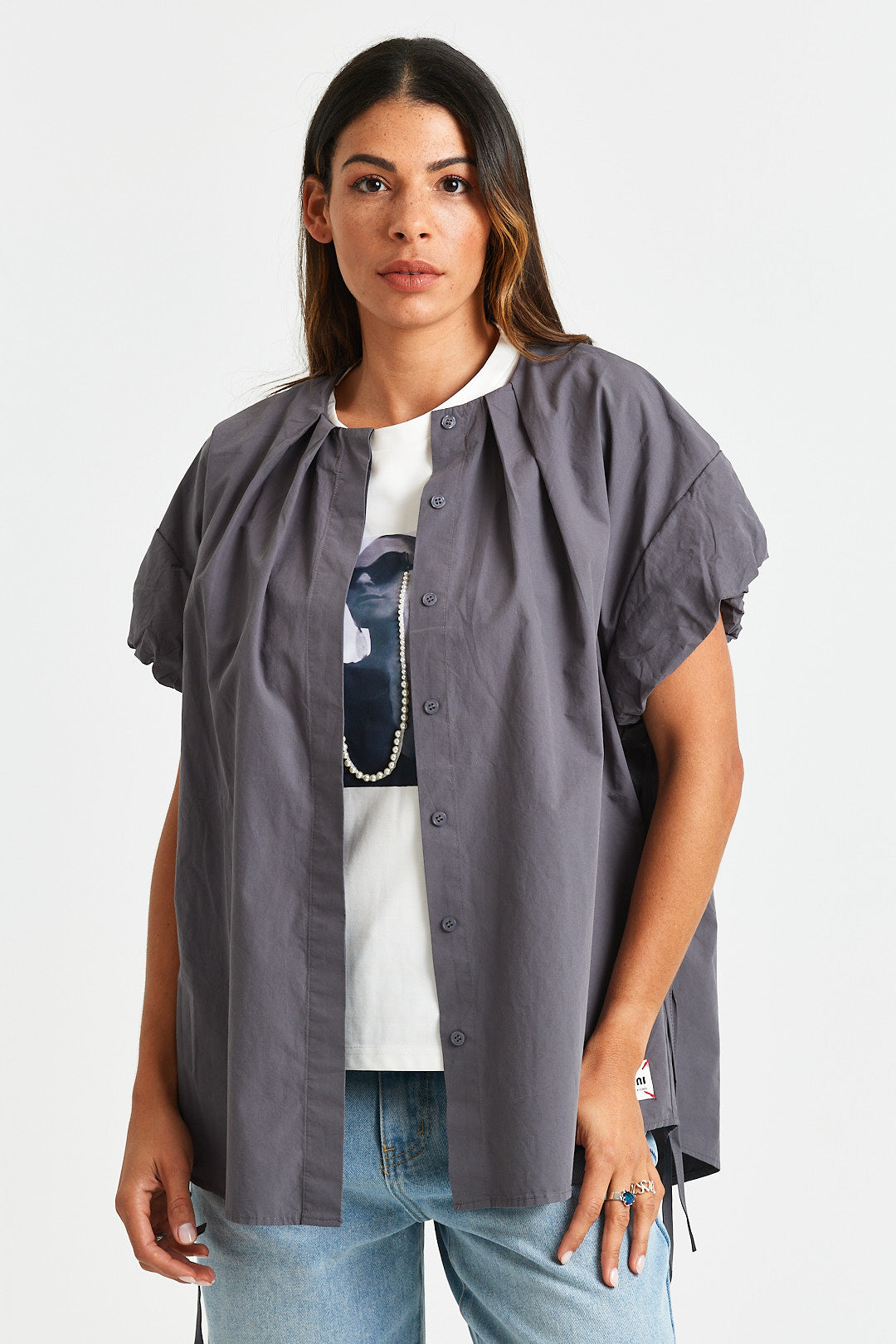 RENE TOP Woman wearing a gray short-sleeve shirt over a white t-shirt with a graphic design, on a plain background.
