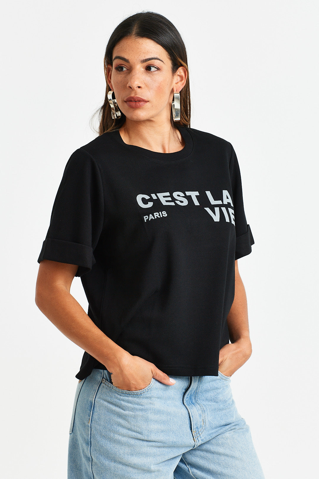FRIDA TEE Woman wearing a black t-shirt with 'Cçest La Vie' text on a white background