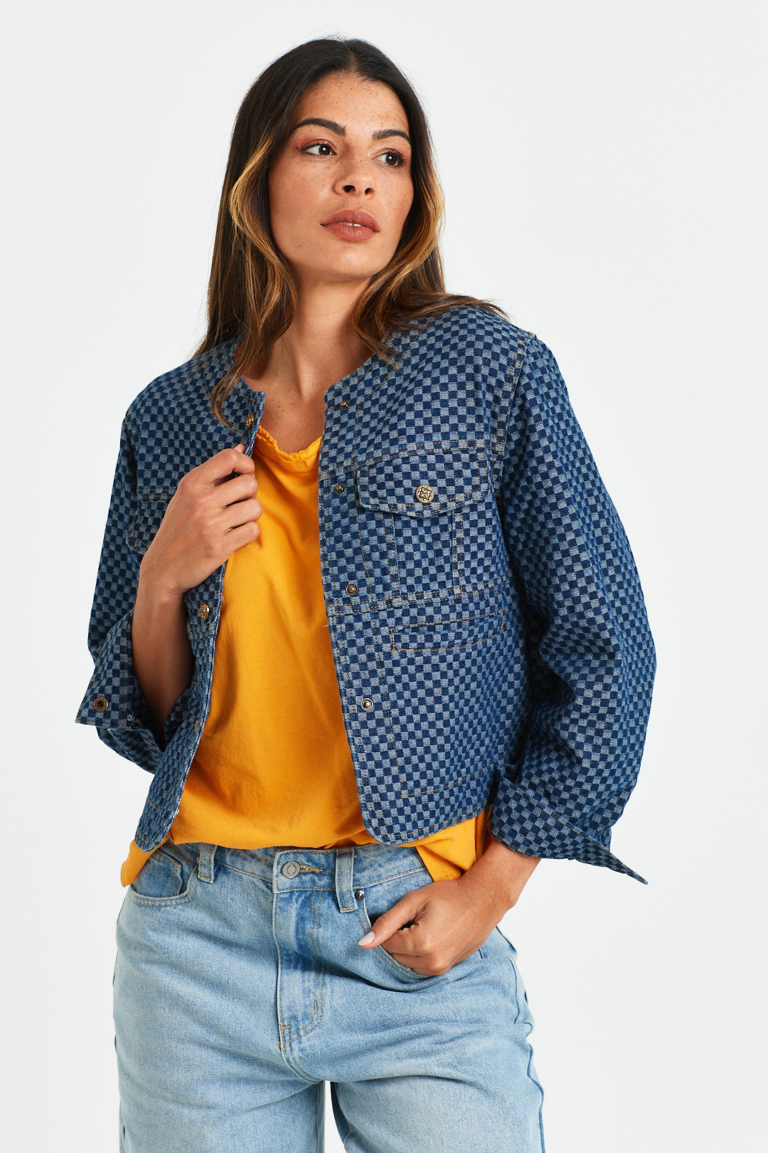 ALVIN JACKET Woman wearing a blue checkered jacket over a yellow shirt with light blue jeans on a white background
