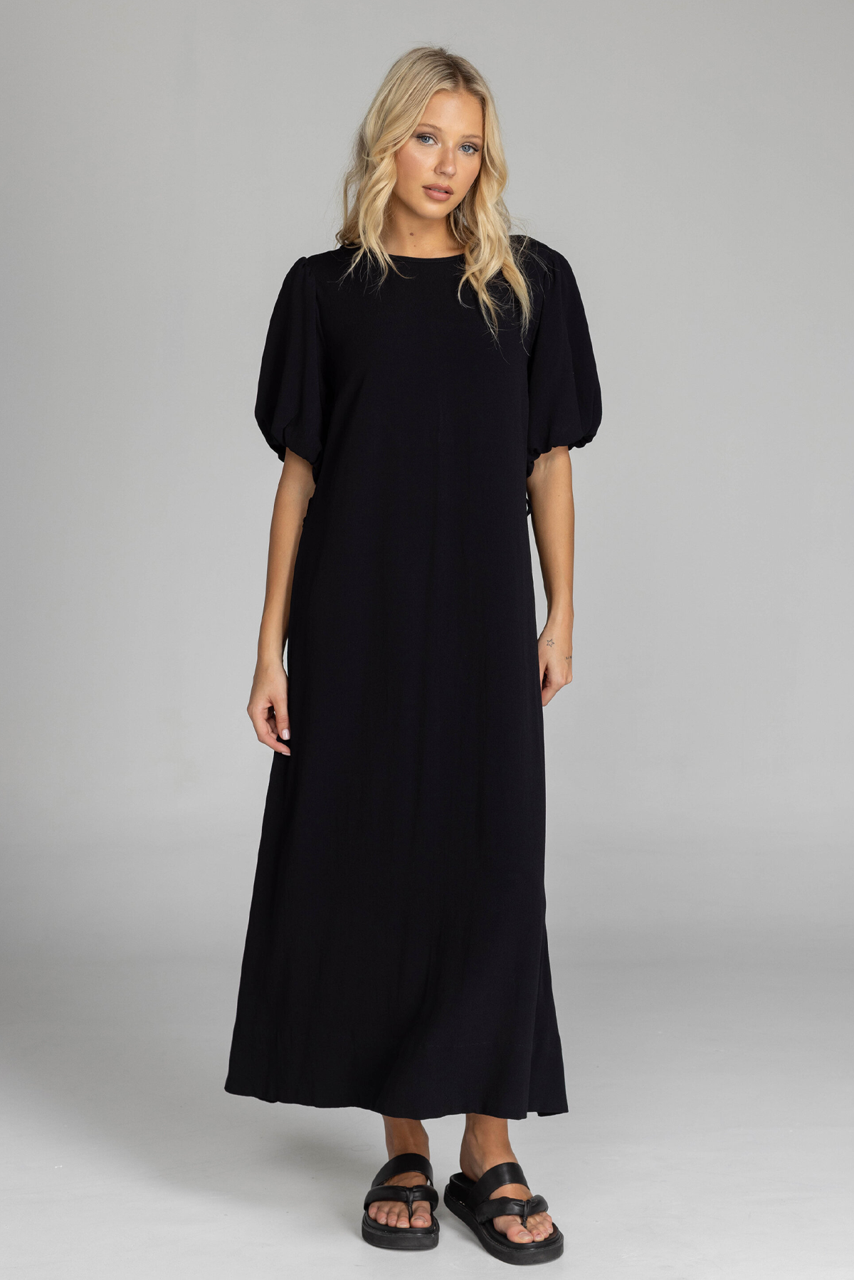 QUIET LOVE DRESS Woman wearing a black dress on a gray background