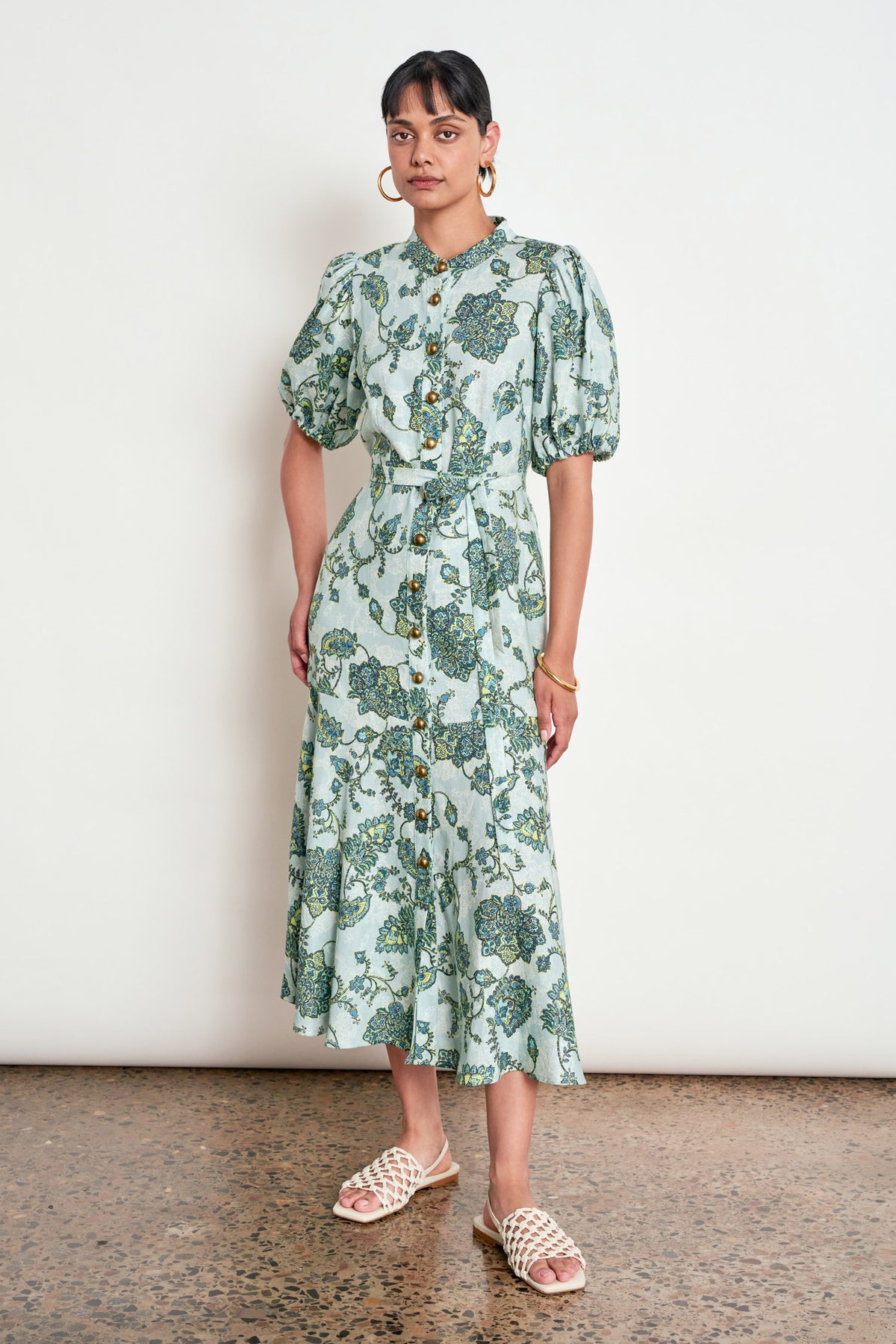 ZOE KRATZMANN CASCADE DRESS FERN PAISLEY - A light green midi dress with a blue and green floral print, featuring puff sleeves, a button-up front, and a tie-waist detail