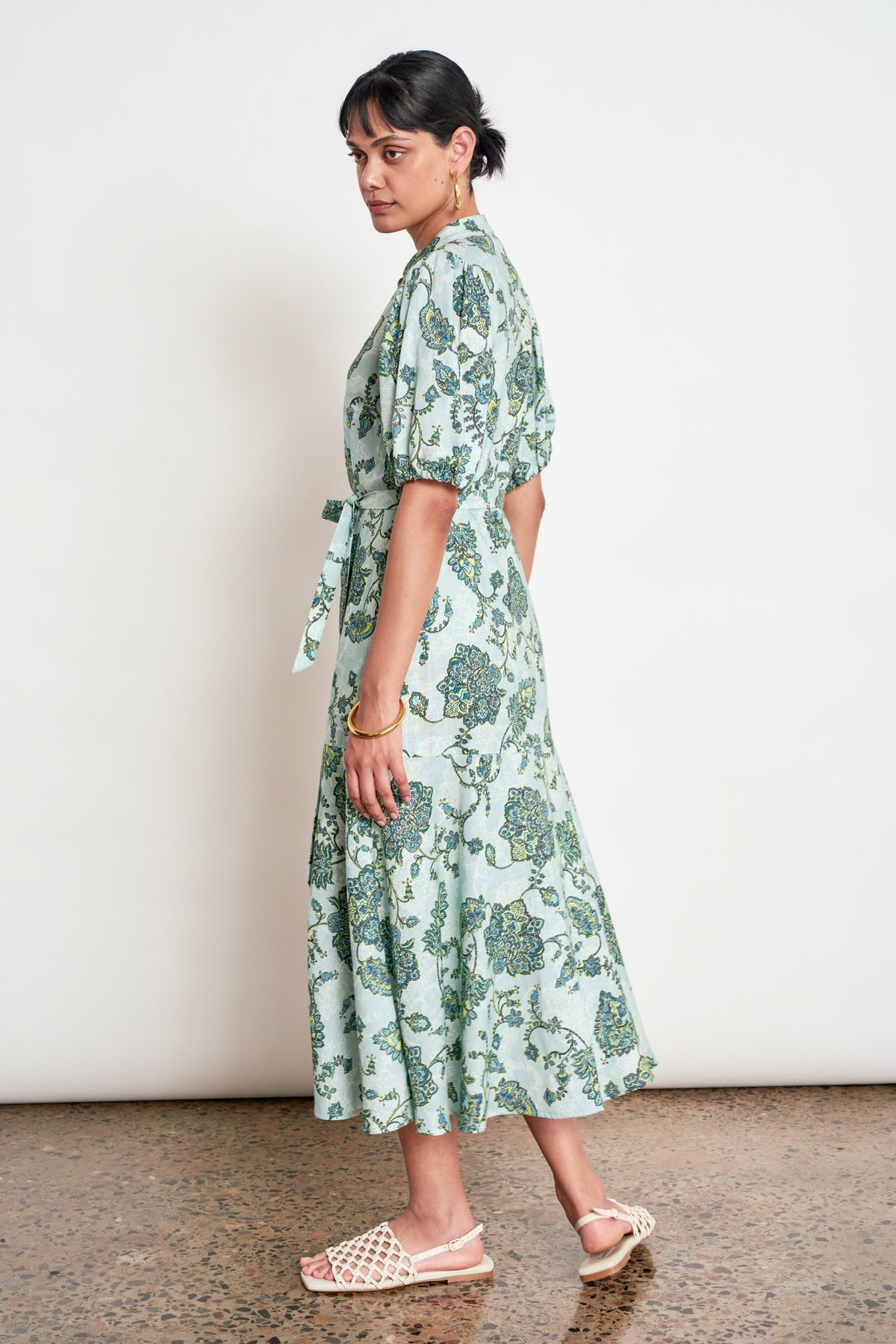 ZOE KRATZMANN CASCADE DRESS FERN PAISLEY - A light green midi dress with a blue and green floral print, featuring puff sleeves, a button-up front, and a tie-waist detail