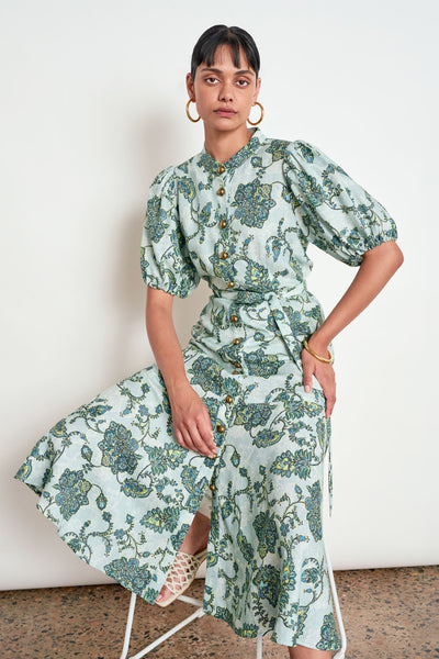 ZOE KRATZMANN CASCADE DRESS FERN PAISLEY - A light green midi dress with a blue and green floral print, featuring puff sleeves, a button-up front, and a tie-waist detail