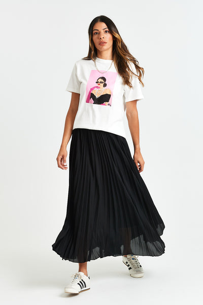 JOY TEE Woman wearing a white t-shirt with a graphic design and a black pleated skirt on a white background