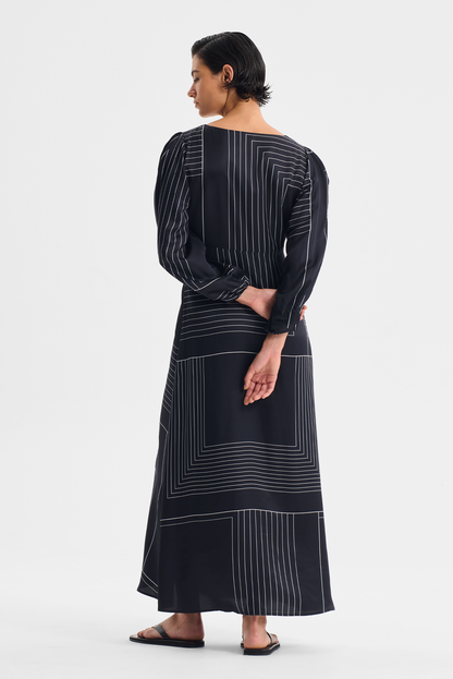 PRIYA DRESS Woman wearing a black dress with white geometric patterns on a white background