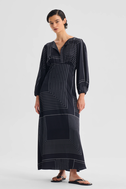 PRIYA DRESS Woman wearing a long black dress with white patterns on a light gray background