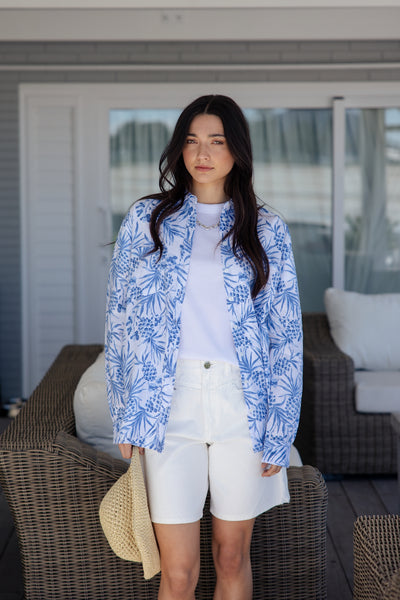 white and blue short-sleeve button-up shirt with a blue tropical print.